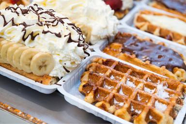 Waffles con diversi toppings: banana e panna, cioccolata, fragole e zucchero