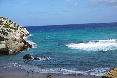 Scogliera bianca e mare blu, con le onde che si infrangono prima di arrivare a riva: è l'isola di Maiorca nell'arcipelago delle Baleari