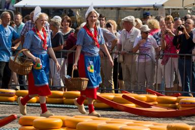 Rievocazione del mercato del formaggio nel Noord Holland. Due ragazze vestite con abiti tradizionali passano tra le forme di formaggio esposte al pubblico.